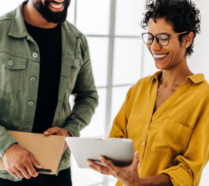 Man and woman smiling looking at a tablet.