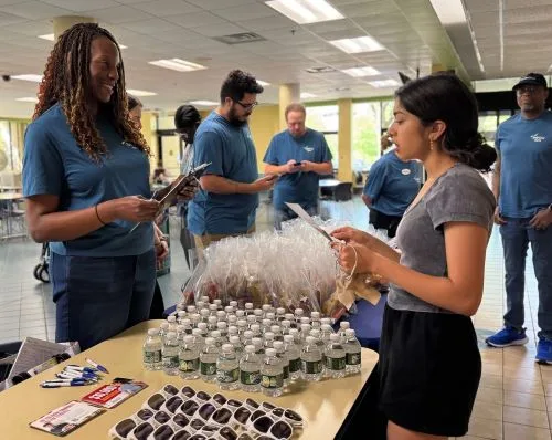 College student talks to volunteer across a table filled with giveaway items