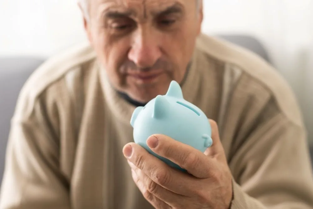 Senior Caucasian man holding piggy bank