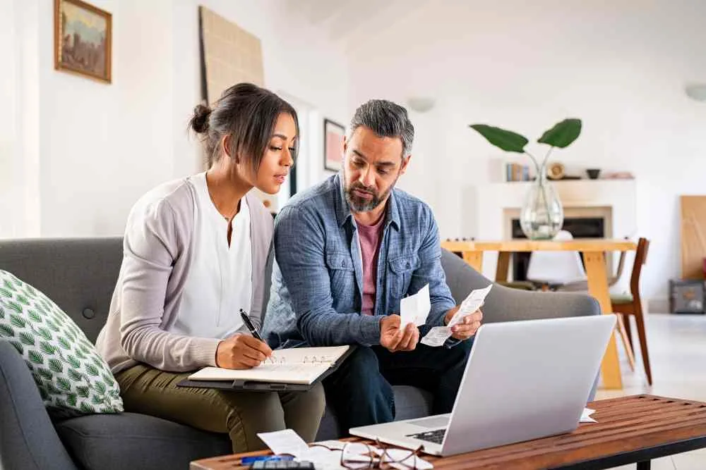 Mature Indian man with African American woman at home analyzing their finance with documents.