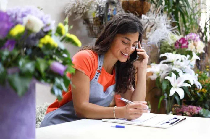 Young woman running the flower shop, making phone calls and organizing the business