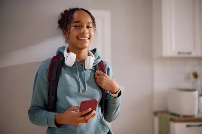 Happy African American female student getting ready for school and looking at camera