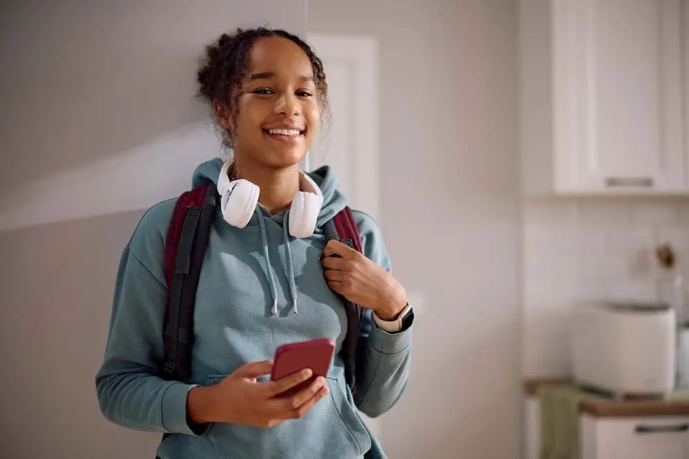 Happy African American female student getting ready for school and looking at camera
