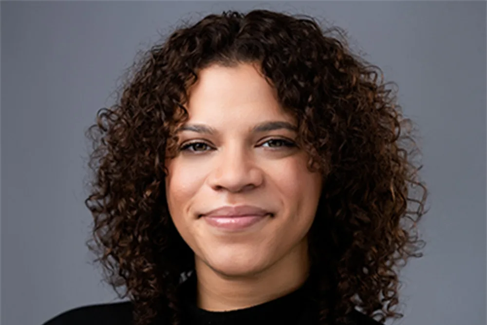 Woman with dark curly hair smiles