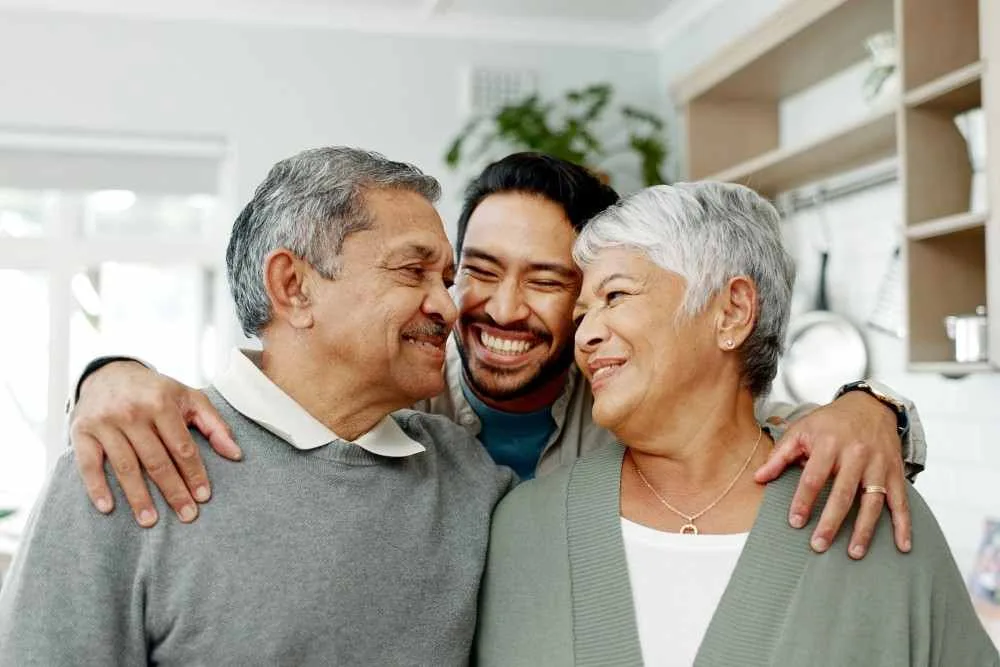 Adult son with his arms around his mom and dad