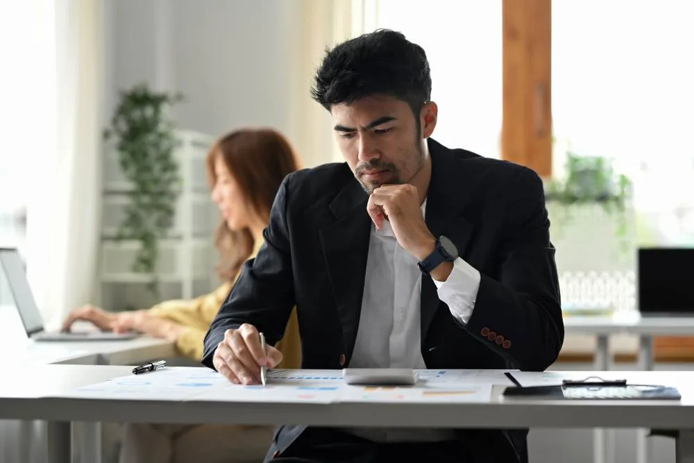 Man sits at desk looking over financial reports