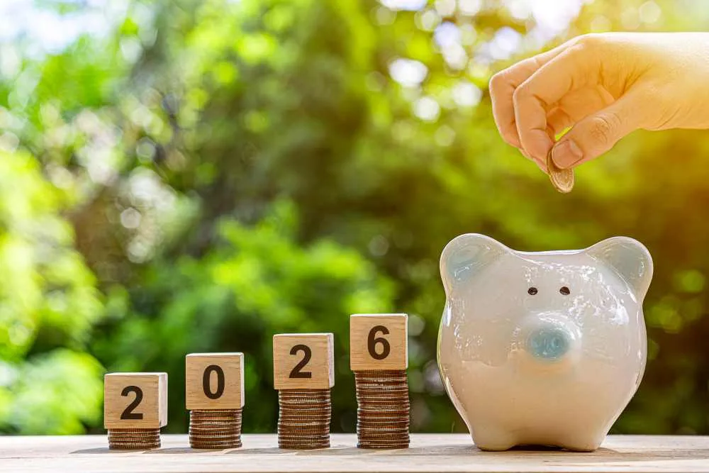 Piggy bank next to blocks stacked on coils. Blocks spell out 2026