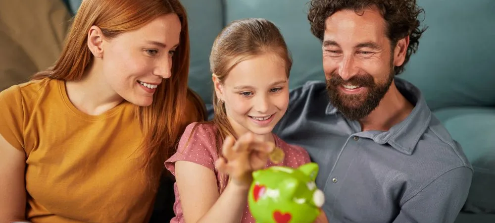 Family saving money together with piggy bank at home