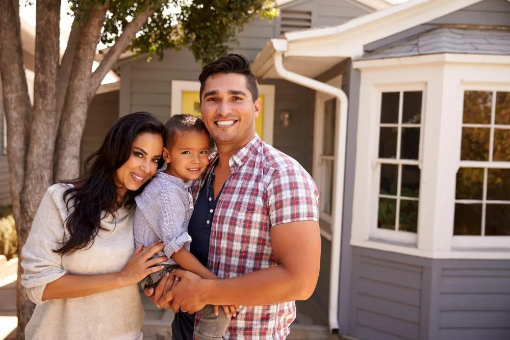 Young parents with child stand outside of their house