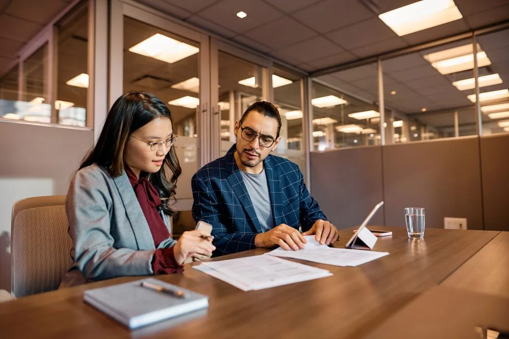 Two business colleagues analyzing documents while working in the office