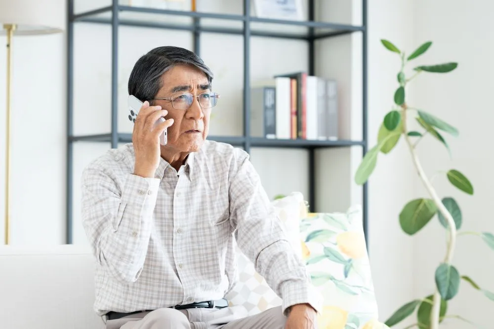 Senior man making a phone call in the living room