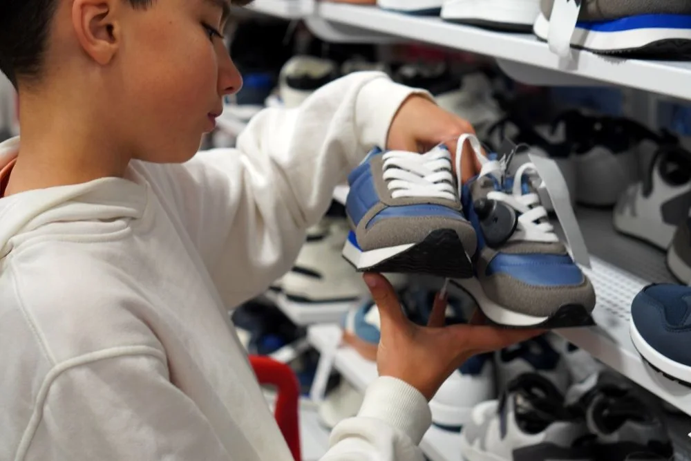 Boy choosing a pair of sneakers in a clothing store