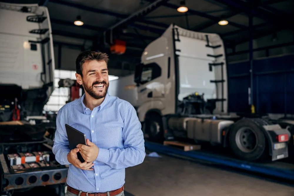 Man holds tablet in front of trucks in auto shop