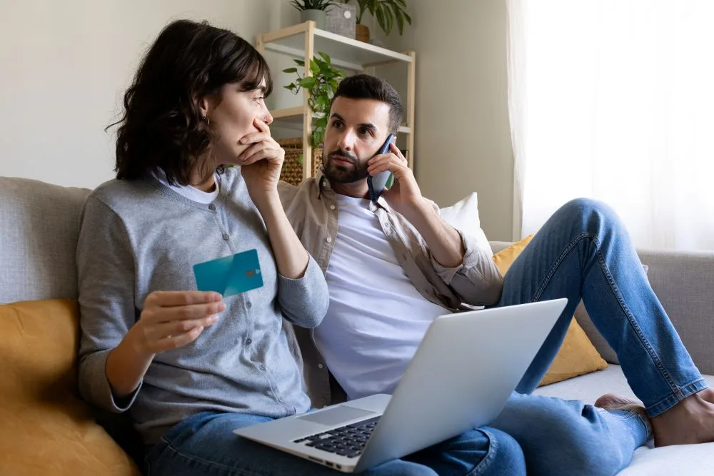 Man and women sit on couch, talking on phone, worried about identity theft