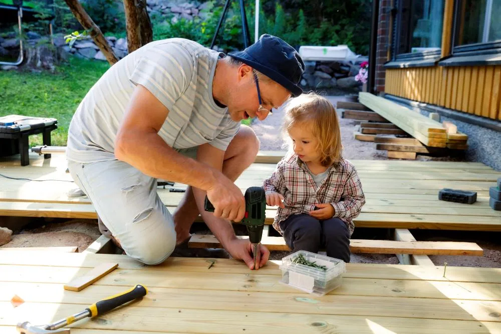 Father works with young daughter to build a patio deck